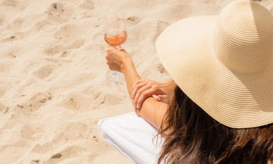 Woman on the beach holding a glass of Whispering Angel
