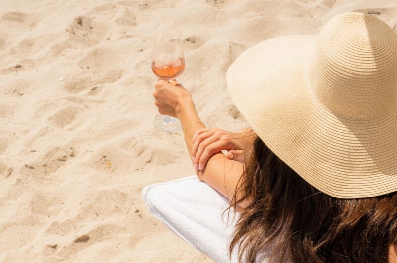 Woman on the beach holding a glass of Whispering Angel