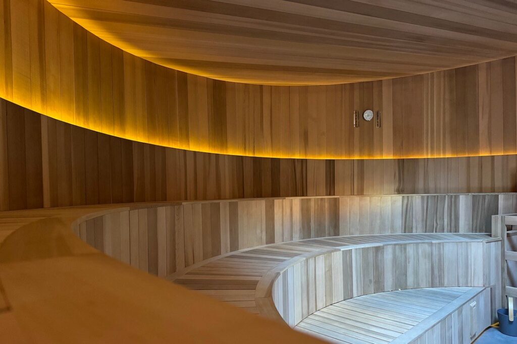 Curved wooden benches inside the sauna at Alchemy Springs & Sauna Garden in San Francisco
