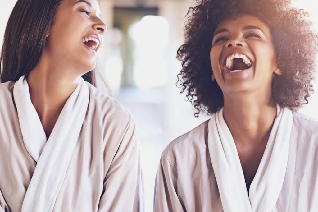 Two friends in spa robes laughing together