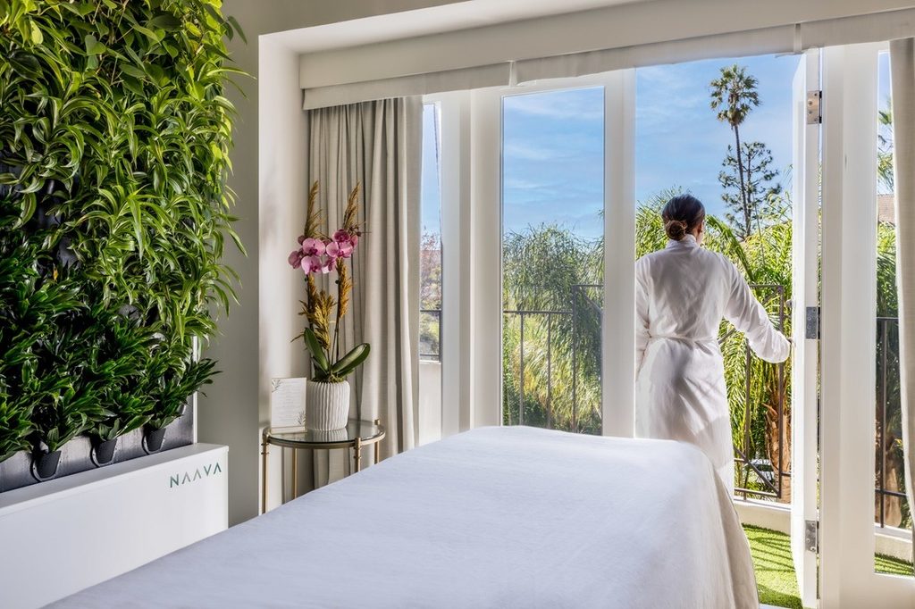 Spa guest in a robe stepping out onto a balcony from a treatment room