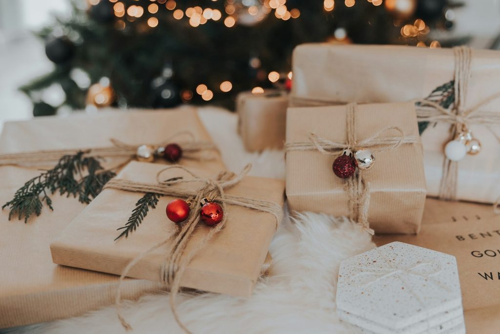 Experience gifts wrapped in brown paper with holiday greenery