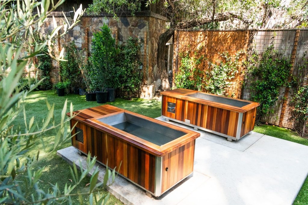 Outdoor cedar cold plunge tubs in a garden spa courtyard