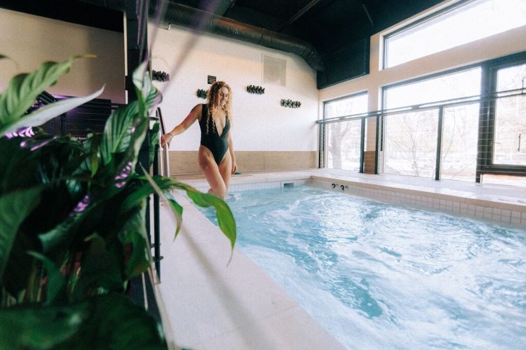 Woman stepping into a warm soaking pool at Soak & Sage in Renton, Washington